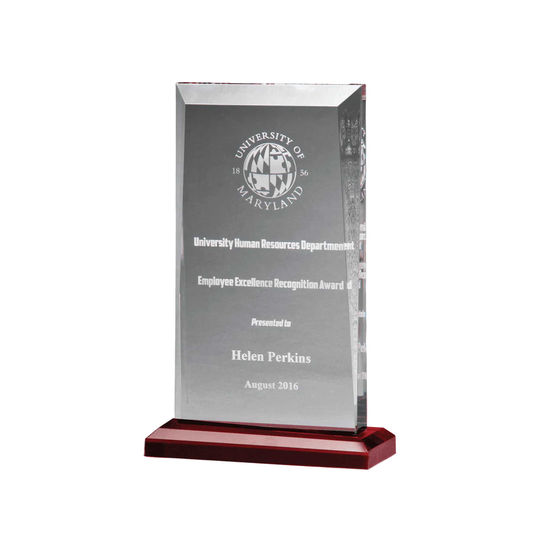 Clear glass award with engraved text on a red base against a gray background