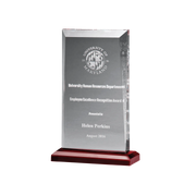 Clear glass award with engraved text on a red base against a gray background