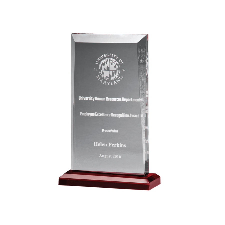 Clear glass award with engraved text on a red base against a gray background
