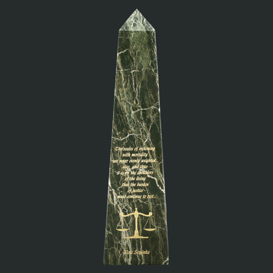 Green marble obelisk with engraved text and a scale symbol
