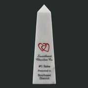 White marble obelisk with a red heart design and text on a white background