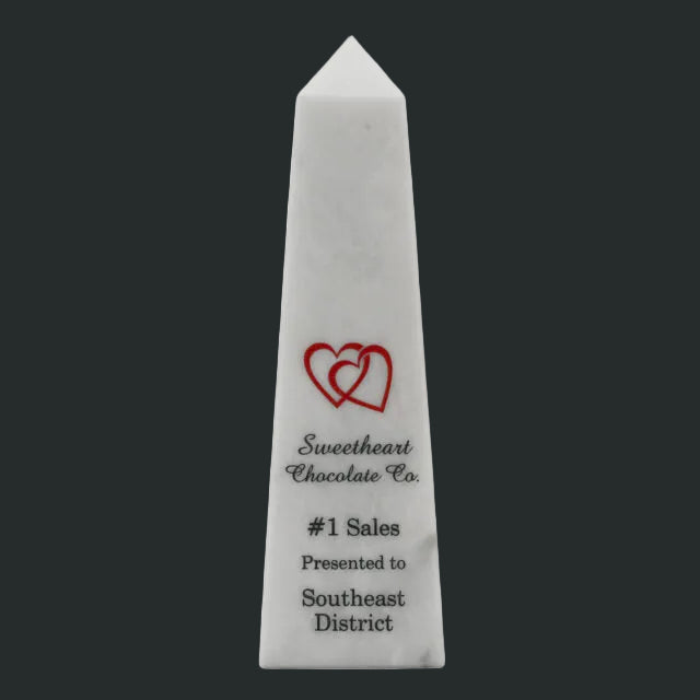 White marble obelisk with a red heart design and text on a white background