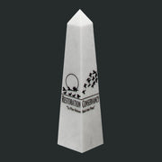 White obelisk with black text and design on a gray background